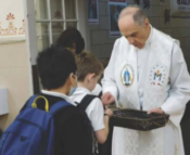 Priest giving out Miraculous Medals to children