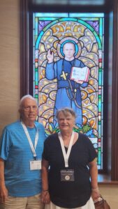 Man and woman standing at stained-glass window of St. John Neumann